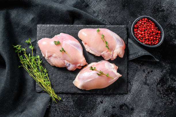 istock Chicken thigh fillet without skin. Black background. Top view 1254894511