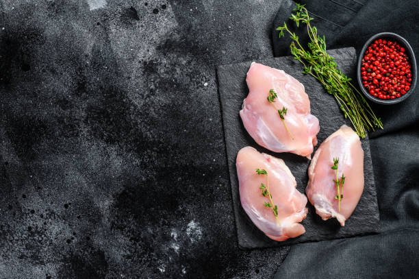 istock Raw boneless chicken thighs fillet. Black background. Top view. Copy space 1254894589