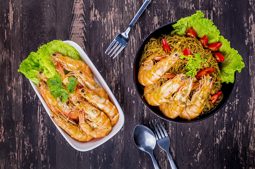 Baked shrimp with glass noodles on dark wooden background