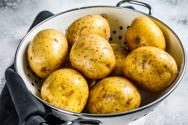 istock Raw washed potatoes in a colander. Gray background. Top view 1254896751