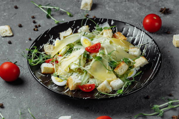 istock Fresh Caesar salad in a black plate on a gray background.Top view 1254896937