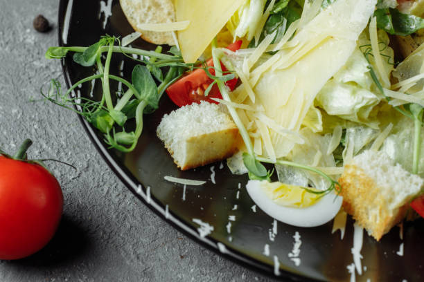 istock Fresh Caesar salad in a black plate on a gray background.Top view 1254896972