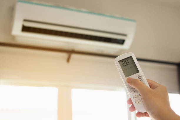 istock Hand with remote control directed on air conditioner inside the room 1254898175