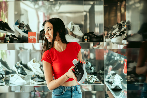 Smiling young lady shopping for shoes at a shoe store.