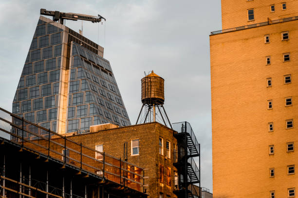 Roof water tower in Manhattan with a modern office building in the background at sunset, New York City