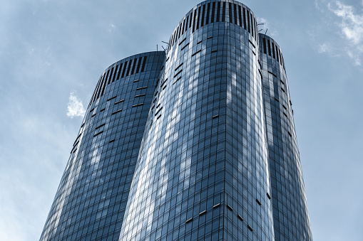 Modern glass high-rise office building in New York seen from below against a blue sky.