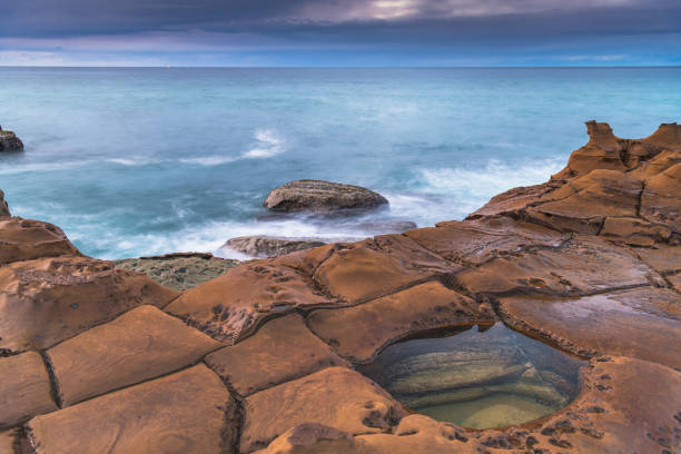 istock Rain Clouds and a Sunrise Seascape from Rock Platform 1254905566