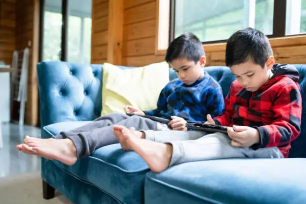 Mixed race kids at home using smart tablets to play games.