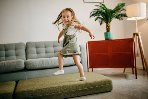 子供はソファに飛び乗る - domestic life jumping child sofa ストックフォトと画像