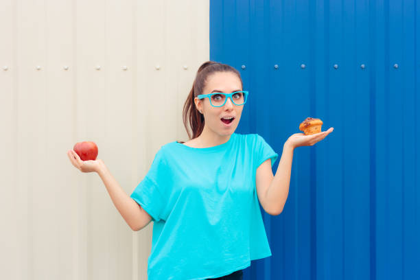 istock Cheerful Woman on a Diet Choosing Between Apple and Muffin 1254912331