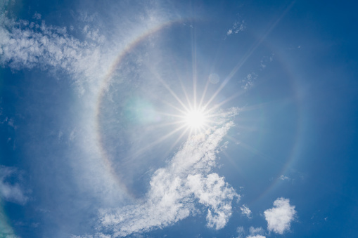 phenomenon sun halo on blue sky with sunbeams and clouds in the day