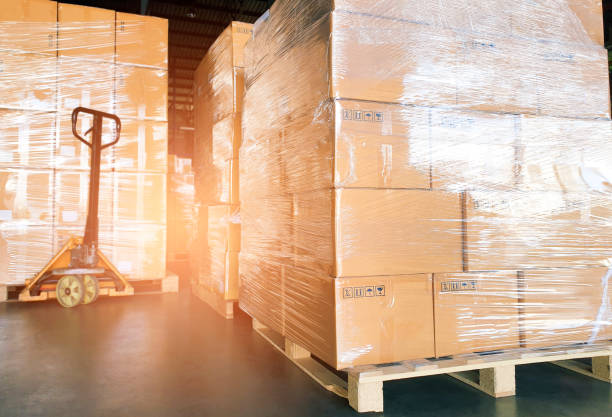 istock Stack of many shipments boxes on pallet at interior warehouse storage. Package boxes on pallets and hand pallet truck. Cargo export. Warehouse industry shipping logisics and transportation. 1254914762