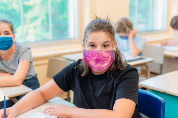 istock A thirteen year old student is looking at the camera while sitting at her desk in class with a mask to protect herself from Covid-19. 1254919926