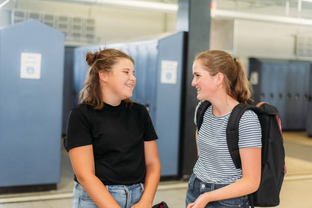 istock Two thirteen year old students are chatting around lockers at school. 1254919985