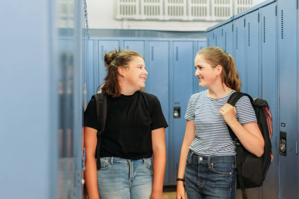 istock Two thirteen year old students are chatting around lockers at school. 1254920032