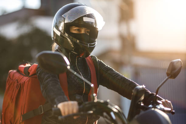 Female biker riding a motorcycle- Motogirl, Motoboy Delivery woman - motogirl biker helmet mask stock pictures, royalty-free photos & images