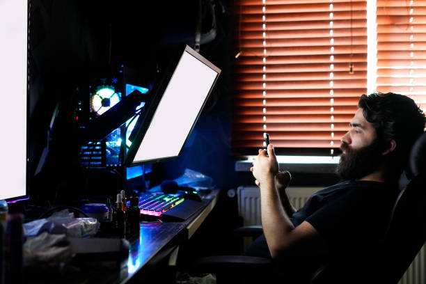 istock bearded man gamer designer freelancer working on high end computer using smartphone 1254922373