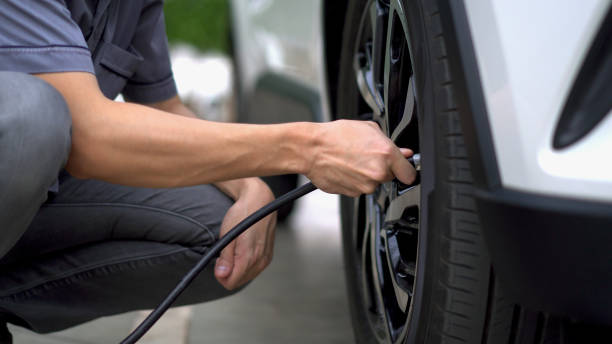 man filling air in the tires of car (inflating tire) - inflating imagens e fotografias de stock