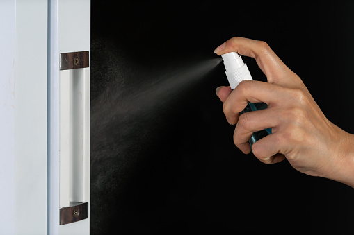 hand spraying alcohol to cleaning door knob for protect from infection of virus and germ Covid-19 coronavirus