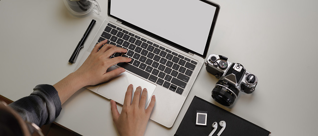 Overhead shot of female photographer working on modern office desk with mock-up tablet, camera and supplies