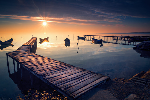 Beautiful sunrise or sunset on a calm lake with several fishing boats  and wooden pontoons