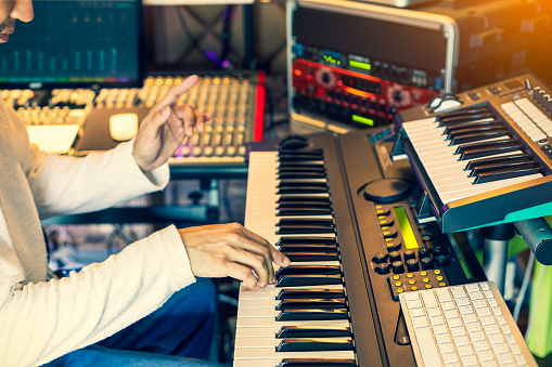 male musician, producer, composer playing electric piano in home studio