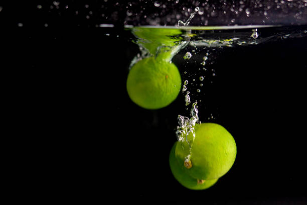Green limes in water on a black background