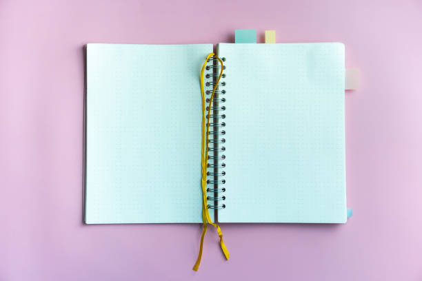 istock Top view of blank space white notebook and pen with tropical leaf as frame background. 1254944935