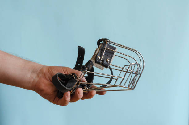 bozal metálico con correas de cuero para un perro en una mano masculina. - bozal fotografías e imágenes de stock