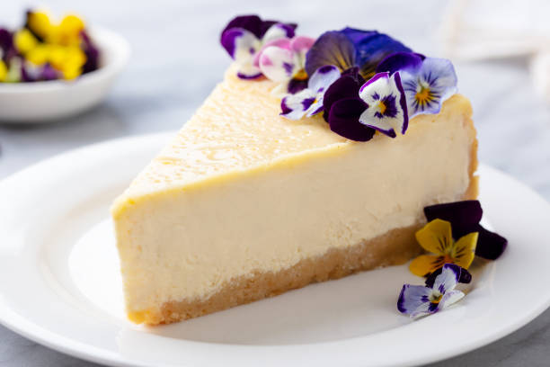 istock Cheesecake decorated with edible flowers on white plate. Marble background. 1254946868