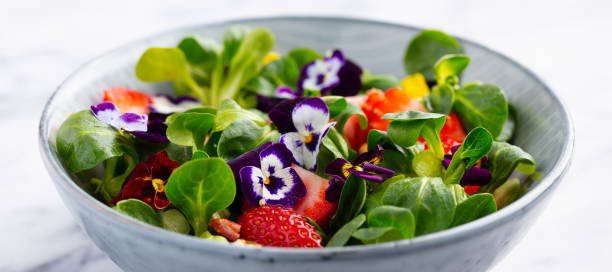frischer grüner salat mit erdbeeren und essbaren blumen in einer schüssel. marmor hintergrund. nahaufnahme. - close up green plate salad stock-fotos und bilder