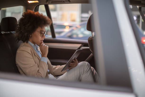 istock Business woman using digital tablet in a car 1254947525