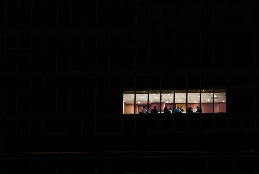 View of workers at meeting in corporate office building at night in Hong Kong