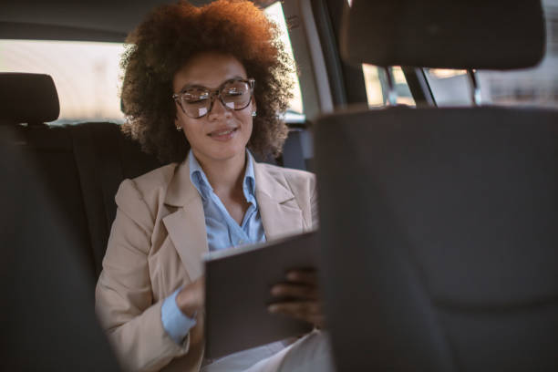 istock Business woman using digital tablet in a car 1254947688