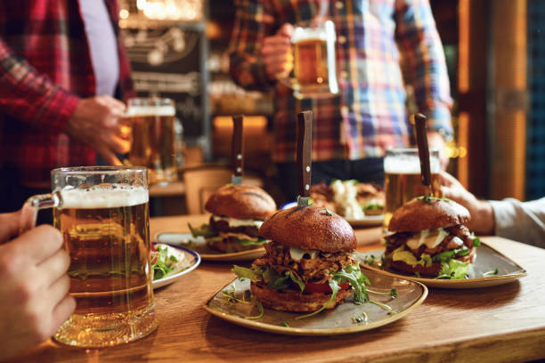 burger mit bier auf dem tisch in einer bar kneipe. - pub food stock-fotos und bilder