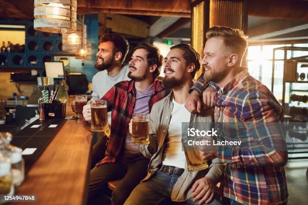A Group Of Guys Watching Sports On Tv In A Pub Bar Stock Photo - Download Image Now
