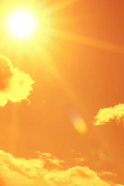 Bright sun with beautiful beams in the sky with clouds. Toned in orange color, space for copy.