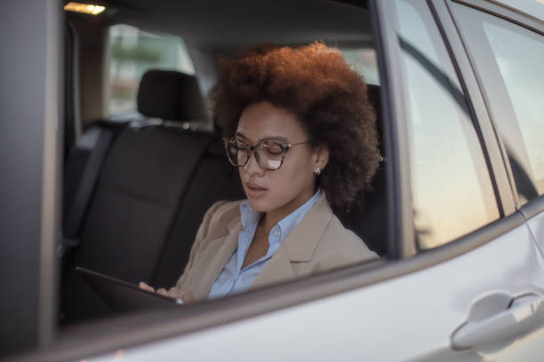 istock Business woman using digital tablet in a car 1254947968