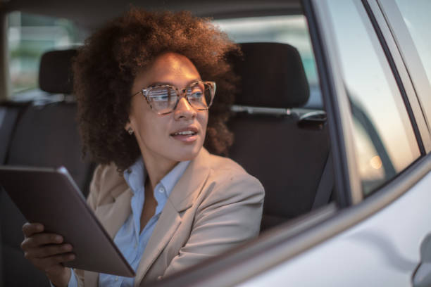 istock Business woman using digital tablet in a car 1254948035