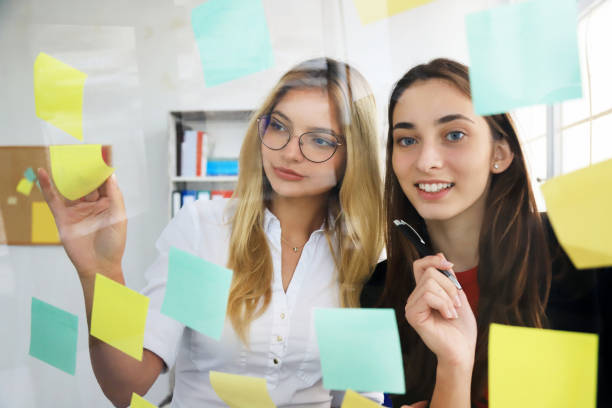 istock Two businesswomen looking at sticky notes 1254948893