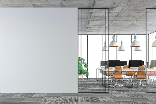 Empty office interior with copy space on carpet floor. Wordesks, lighting and computer equipment and windows in background behind glass door. Slight cross process effect added. 3D rendered image.