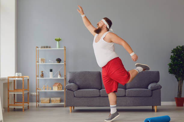 istock Funny red fat man doing exercises while standing at home. 1254953725