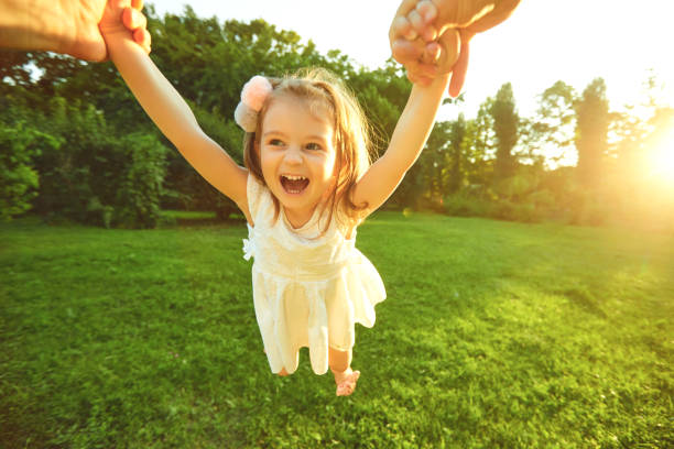 istock Happy child is twisted by hands in the park. 1254953843