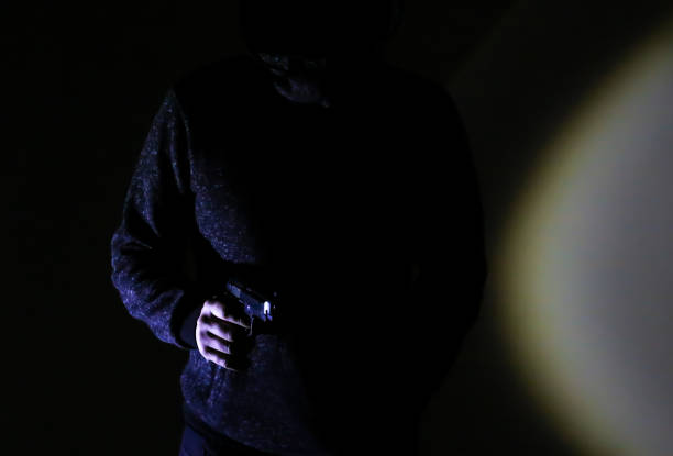 istock Man with gun. Shadow in the spotlight. Criminal concept. 1254954554