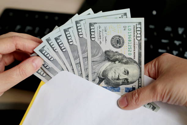 istock Envelope with US dollars in female hands 1254955414