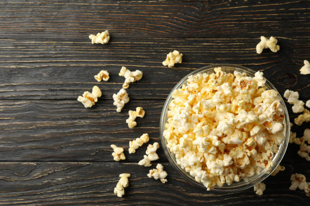 istock Bowl with popcorn on wooden table. Food for watching cinema 1254957230