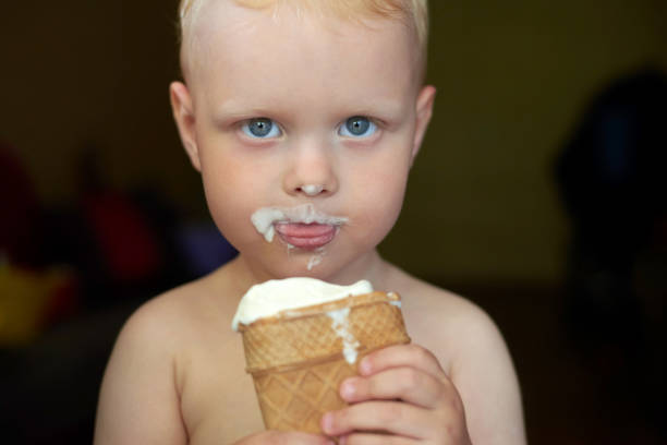 istock Little blue-eyed fair-haired boy eats ice cream. 1254957451