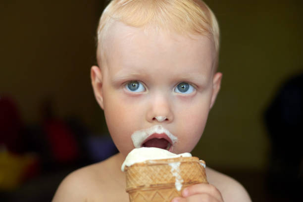 istock Little blue-eyed fair-haired boy eats ice cream. 1254957468