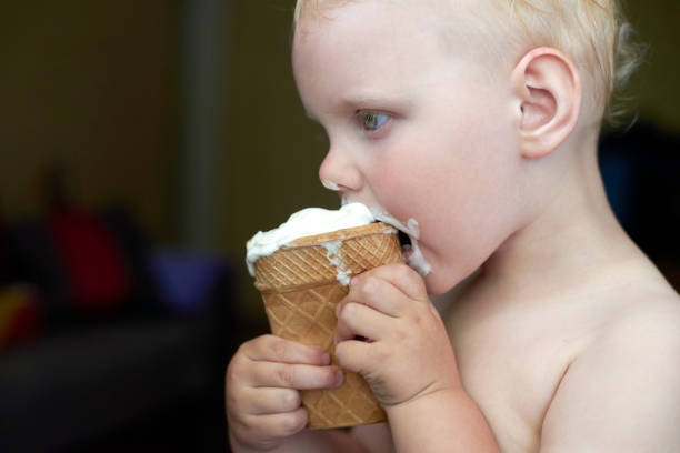 istock Little blue-eyed fair-haired boy eats ice cream. 1254957492