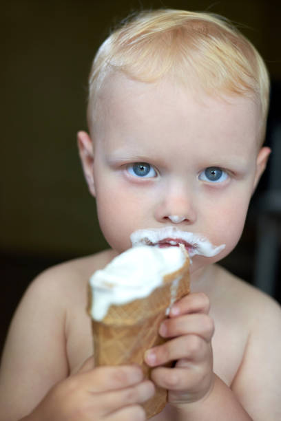 istock Little blue-eyed fair-haired boy eats ice cream. 1254957520